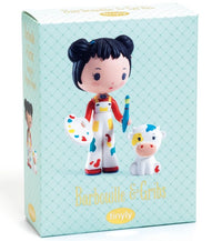 The DJECO Tinyly Barbouille & Gribs toy box features a collectible DJECO figure set, including a doll with dark hair styled in buns, holding a paintbrush and palette, standing beside a small white cow with a yellow spot. Perfect for fans of collectible figures and imaginative pretend play, the box displays "Barbouille & Gribs" and "tinyly" against a blue patterned background.