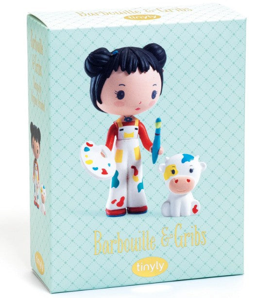 The DJECO Tinyly Barbouille & Gribs toy box features a collectible DJECO figure set, including a doll with dark hair styled in buns, holding a paintbrush and palette, standing beside a small white cow with a yellow spot. Perfect for fans of collectible figures and imaginative pretend play, the box displays "Barbouille & Gribs" and "tinyly" against a blue patterned background.