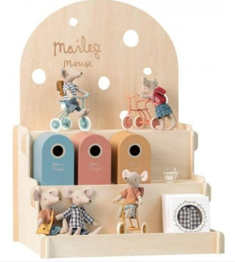 The Maileg Mouse Display - Wood by Maileg showcases charming toy mice and their accessories, with mice sitting, biking, or relaxing on shelves alongside colorful boxes and a round, checked piece. "Maileg mouse" is displayed at the top.