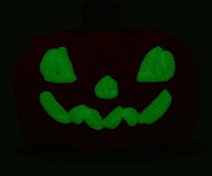 Hal the Jack-o-Lantern Crochet Kit by The Woobles features a glowing green jack-o'-lantern face—arched eyes, triangle nose, and wide jagged smile—great inspiration for beginner crochet projects or a festive crochet kit.