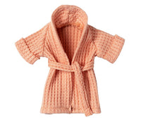 A small Maileg Bathrobe for Mum Mouse in a coral waffle-knit fabric, featuring a front-tied belt, perfect for pretend play and displayed against a white background.