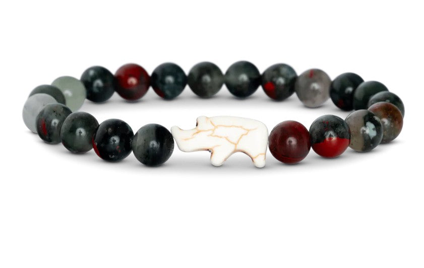 The Charge - Savanna Stone Rhino bracelet by fahlo features dark green, black, and red beads with a white bear-shaped centerpiece—an ideal accessory for supporting wildlife conservation.